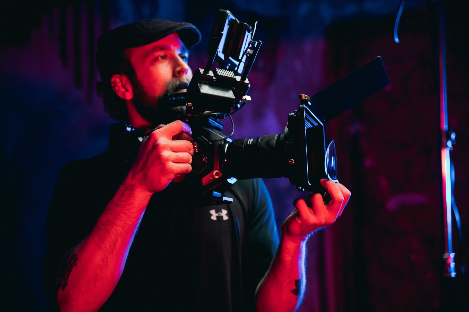 A cinematographer holding a professional camera rig on an indoor film set.